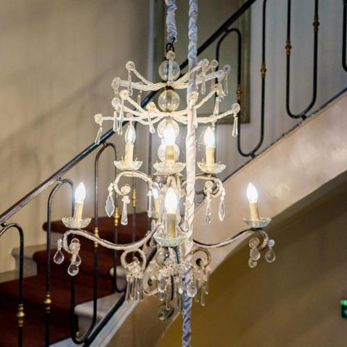 a chandelier with candles is hanging from a staircase at Best Western Plus d'Europe et d'Angleterre in Mâcon