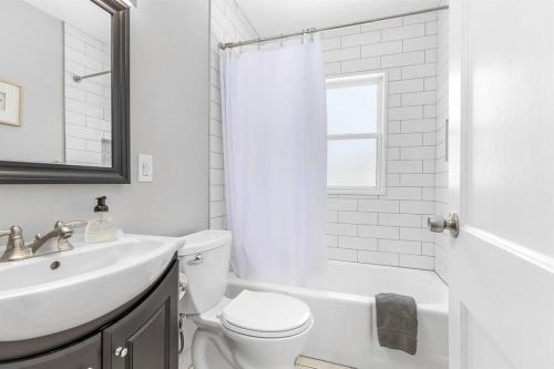a white bathroom with a sink and a toilet at 4 Bedroom Bungalow in the - Heart of Metro Detroit in Center Line
