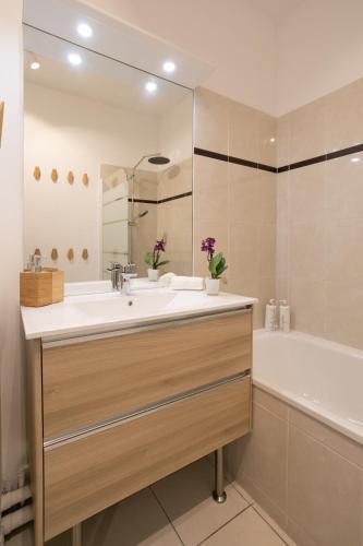 une salle de bain avec un lavabo, une baignoire et un miroir dans l'établissement Lovely Cosy Apartment Terrace - 5 min DISNEYLAND Paris, à Serris
