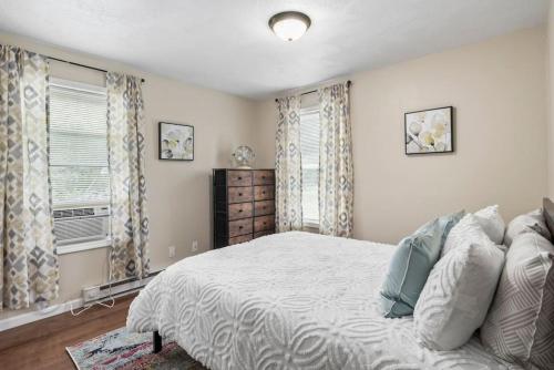 a bedroom with a large bed and two windows at Hot Tub! LRG Home! Sleeps 16!Near Ithaca! Dogs OK in Lansing