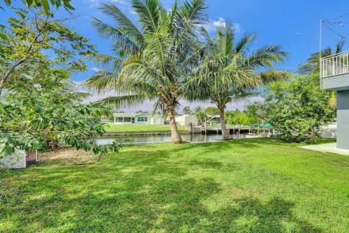 a yard with palm trees and a house at Hot Tub! Roof Top! Firepit! Boat Dock! in Fort Lauderdale