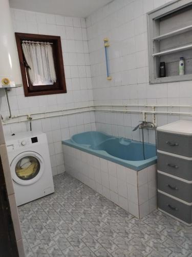 a bathroom with a tub and a washing machine at Stan na dan Vanja in Čačak