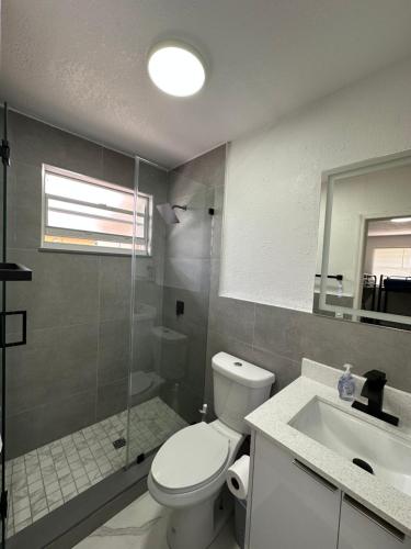 a bathroom with a toilet and a shower and a sink at Wynwood Beds in Miami