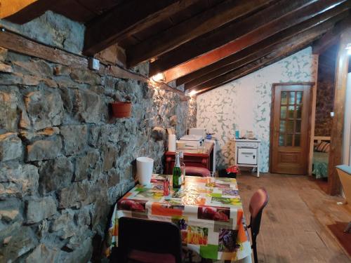 a dining room with a table and a stone wall at Loma Bonita in Valdició