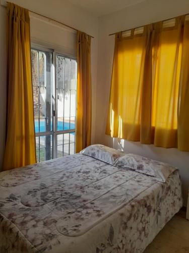 a bedroom with a bed and yellow curtains and a window at Casa con piscina y parrillero in San Juan