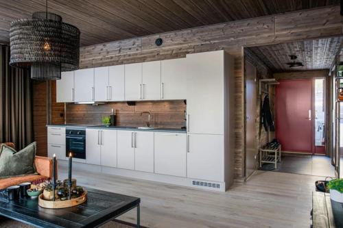 eine Küche mit weißen Schränken und einem Tisch im Zimmer in der Unterkunft New ap The Nest in Hafjell ski in out and fast Wifi in Øyer