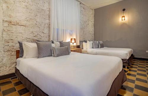 2 camas en una habitación de hotel con sábanas blancas en 3CM-1 CASA COLONIAL DE 3 HABITACIONES CON PISCINA EN EL CORRALITO DE PIEDRA, en Cartagena de Indias