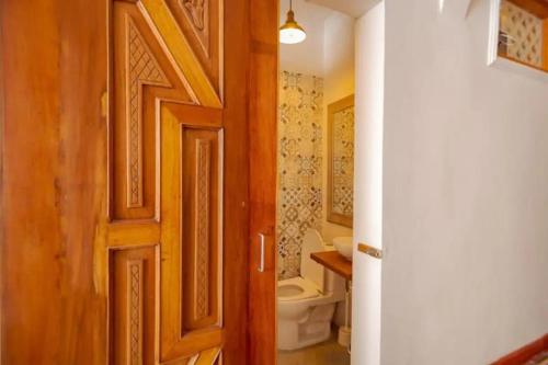 a bathroom with a toilet and a wooden door at 3CM-1 CASA COLONIAL DE 3 HABITACIONES CON PISCINA EN EL CORRALITO DE PIEDRA in Cartagena de Indias