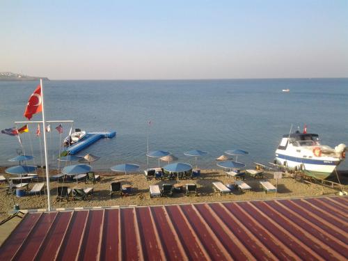 a beach with chairs and a boat in the water at Bells Motel in Seferihisar