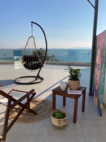 a patio with a swing chair and a table at Wide Blue Luxury Boutique Suites in Neos Marmaras