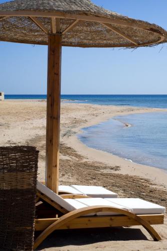 a group of beach chairs and an umbrella on a beach at Shams Prestige Abu Soma (Adults Only) in Hurghada