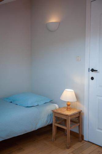 a bedroom with a bed and a table with a lamp at Le Maissin 1876 in Paliseul