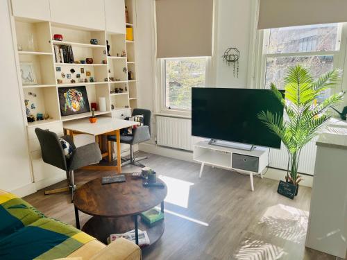 a living room with a large television and a table at Cozy apartment in Hampstead Heath in London