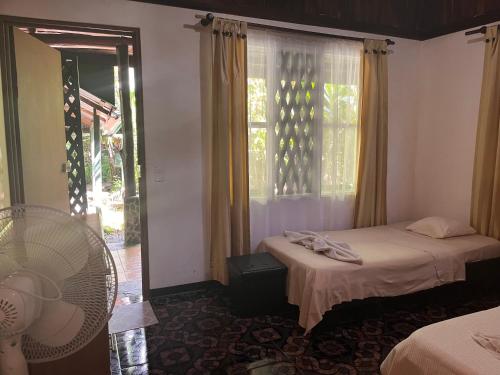 a room with two beds and a fan and a window at Chilamate Rainforest Eco Retreat in Puerto Viejo