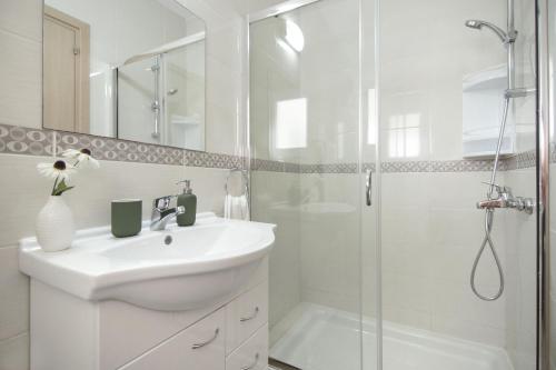 a white bathroom with a sink and a shower at Nissi Sapphire Villa in Ayia Napa