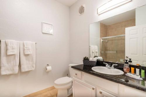 a white bathroom with a sink and a toilet at Apartment 3 BR in Tuscana Resort , 15" from Disney in Kissimmee
