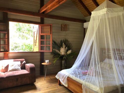 a bedroom with a bed with a mosquito net at Bungalow L’Eden in Les Abymes