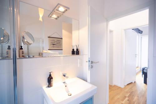 a bathroom with a white sink and a mirror at Willem und Konsorten - Fuchsbau in Heiligenhafen