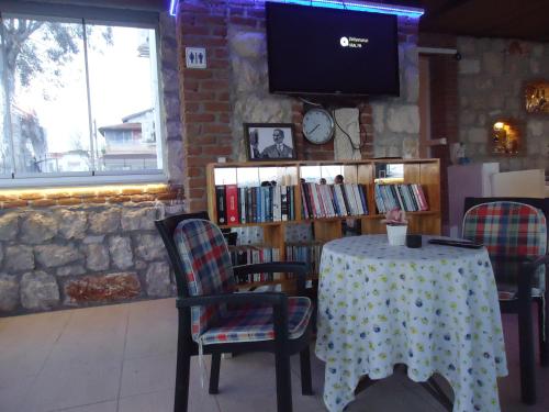 a table with chairs and a tv on a brick wall at Bells Motel in Seferihisar