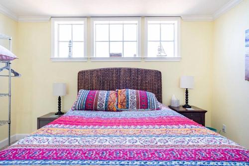 a bedroom with a bed with a colorful bedspread and two windows at Oceanfront at The Dawns in Galveston