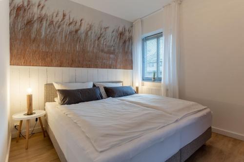 a bedroom with a large white bed with a painting on the wall at Koje 34 in Sankt Peter-Ording