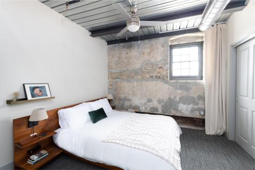 a bedroom with a white bed and a brick wall at Brewery District 2-Story 2BR Apt Near Fiserv with Rooftop, Gym, and Parking in Milwaukee
