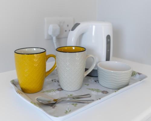 two cups and forks and spoons sitting on a tray at The Doneraile Room 2 in Waterford