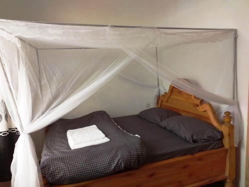 ein kleines Bett mit Baldachin in einem Zimmer in der Unterkunft La-Domek Traveller's home in Mbeya