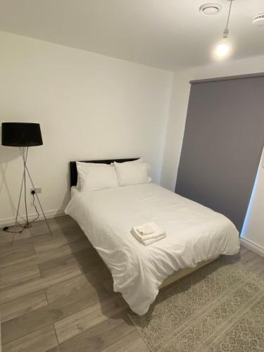 een slaapkamer met een bed met witte lakens en een statief bij 2 Bed Penthouse-Riverside View in East London in Barking