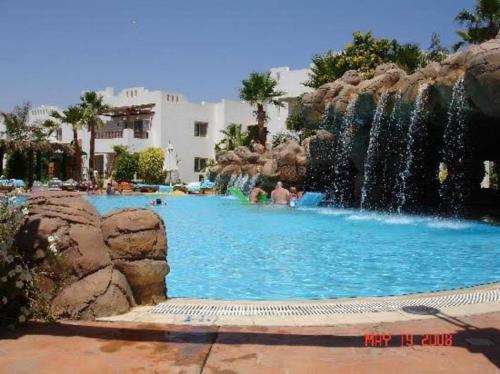 a swimming pool with a waterfall in a resort at Studio Delta sharm Resort in Sharm El Sheikh