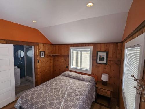 1 dormitorio con paredes de madera, 1 cama y ventana en Stay Twin Lakes Cabin 2, en Twin Lakes