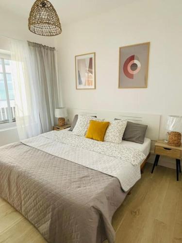 a white bedroom with a large bed with yellow pillows at Apartament Mariola in Calpe