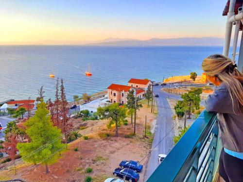 a woman standing on a balcony looking at the ocean at Mitho Hotel Spa in Loutra Edipsou