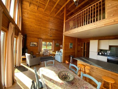 uma cozinha e sala de estar com mesa e cadeiras em Great Glen Holidays - Lone Pine Lodge em Torlundy