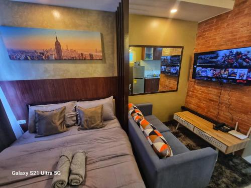 a bedroom with a bed and a couch and a tv at Luxurious Romantic Getaway in a stylish Condo in Tagaytay