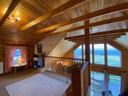 a living room with wooden ceilings and windows in a cabin at Great Glen Holidays - Lone Pine Lodge in Torlundy