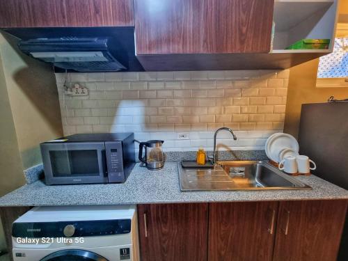 a small kitchen with a sink and a microwave at Luxurious Romantic Getaway in a stylish Condo in Tagaytay