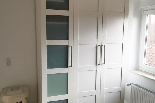 a white cabinet with glass doors in a bathroom at 2 Zimmer Wohnung, Wallbox, Balkon, zentral in Himmelpforten