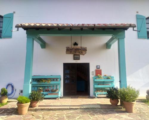 a white building with blue columns and a door at Apartamentos Florinda in Ucieda de Abajo