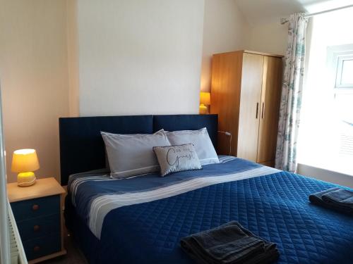 a bedroom with a blue bed with a pillow on it at Copper Mine Cottage in Llandudno