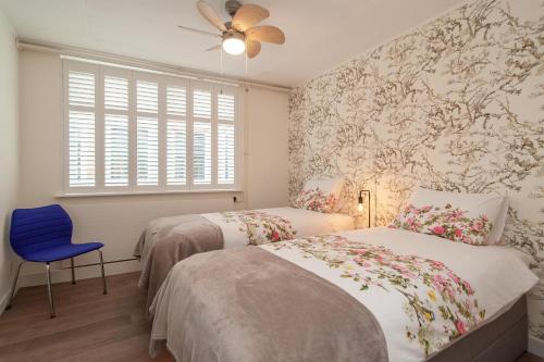 a bedroom with two beds and a blue chair at CASASdeCASPER - Apartment Alkmaar in Alkmaar