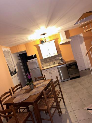 Il comprend une cuisine avec une table et des chaises en bois. dans l'établissement Gîte la grande racinaie, à Cré-sur-Loir