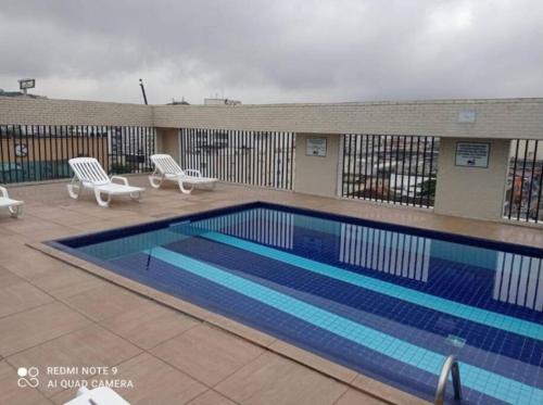 a large swimming pool with two chairs at Flat Palladium in São Vicente