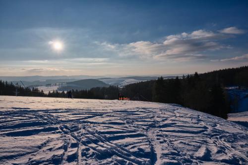 a snow covered slope with the sun in the background at Penzion PANORAMA Janovičky in Broumov