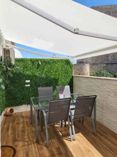 a patio with a glass table and chairs at Bonito Ático en el centro de la ciudad in Sanlúcar de Barrameda