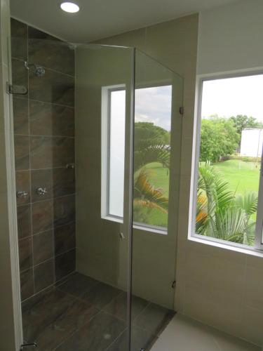 een douche met een glazen deur en een raam bij Habitación Amoblada Tipo Hotel in Tuluá