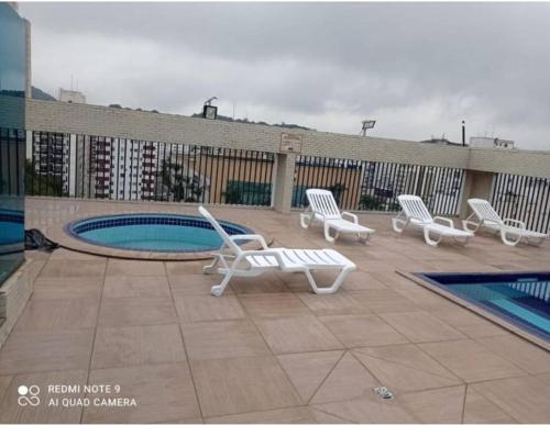 a patio with lounge chairs and a pool on a building at Flat Palladium in São Vicente