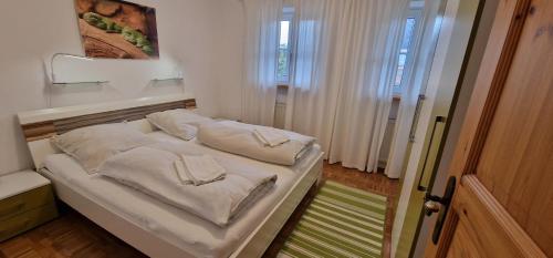 uma cama com almofadas brancas num quarto em ciao-aschau FeWo Wörndl em Aschau
