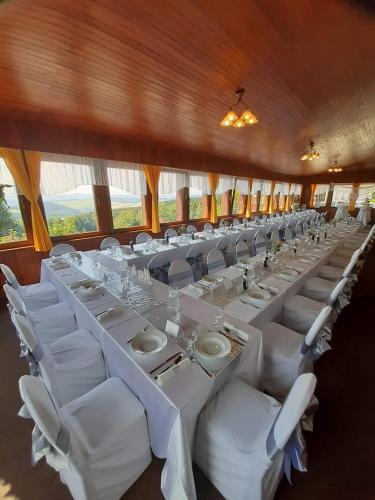 a long dining room with white tables and white chairs at Penzion Vyhlídka Janovičky in Broumov