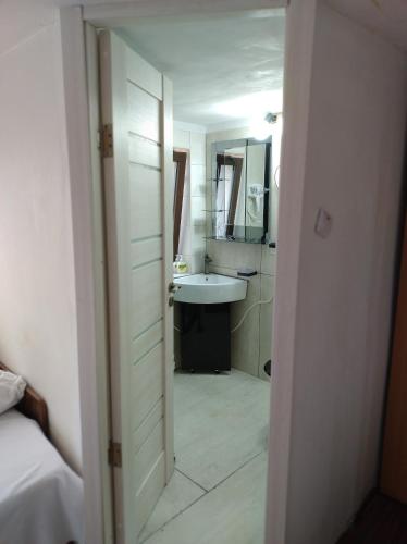 a white bathroom with a sink and a mirror at Studio Grivita in Deva